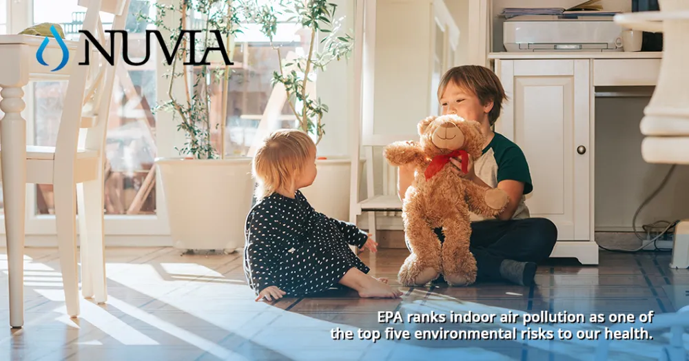 Two children playing on the floor of a sunlit room, with the Nuvia logo and a caption about indoor air pollution